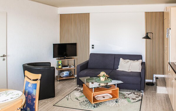 A compact living space with a sofa, a small table, a television, and a cabinet.