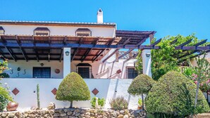 Um edifício tradicional com telhado de telhas, varanda com grades e parede de pedra à frente.