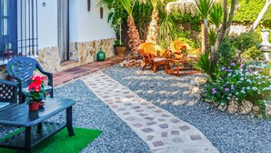Um pátio com caminho de pedra, mobiliário de exterior e plantas em vasos.