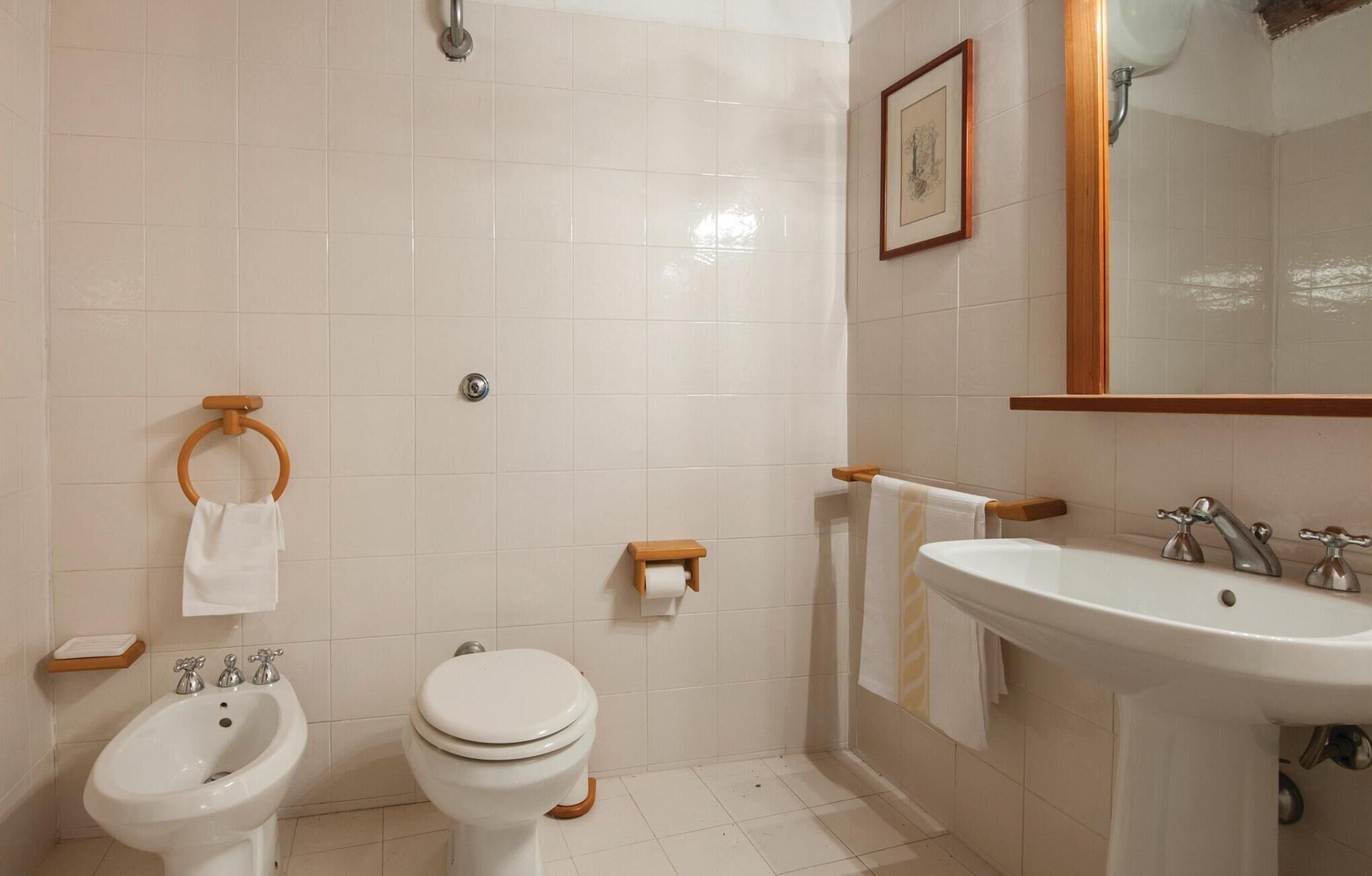 Un baño con bidé, inodoro, lavamanos y un espejo.