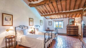 Ein traditionell eingerichtetes Zimmer mit Bett, zwei Nachttischen, einem Schminktisch und einem Fenster mit Aussicht.
