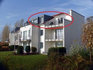 Un edificio residenziale a più piani con balconi, un tetto piatto e un prato curato.