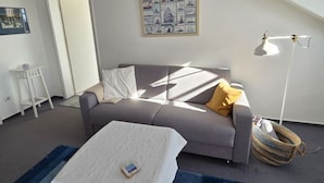 A room with a gray sofa, a white coffee table, a floor lamp, and a framed picture on the wall.