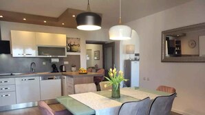 A modern kitchen with built-in appliances, a dining area with a table and chairs, and a large mirror on the wall. - Holiday apartment with balcony and air conditioning (Crikvenica)