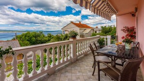 A balcony with a view of the sea, a table with chairs, and a potted plant. - Holiday apartment with balcony and air conditioning (Crikvenica)