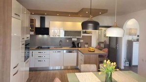 A modern kitchen with white cabinets, a central island, and a pendant light. - Holiday apartment with balcony and air conditioning (Crikvenica)