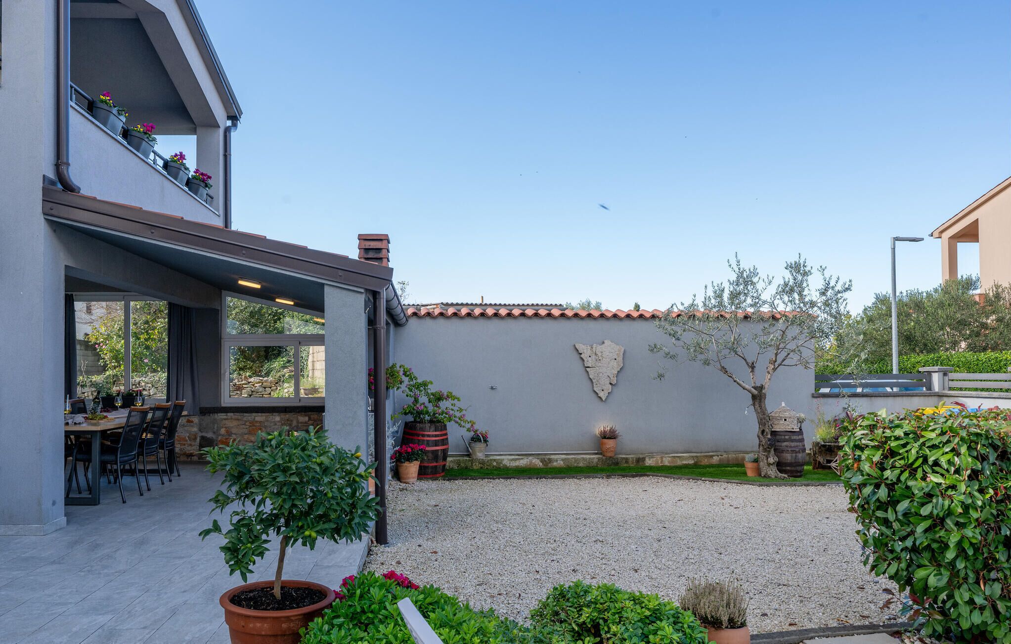 A modern house with a patio, outdoor seating, and a gravel garden.
