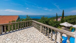 Ein mit Steinplatten belegter Balkon mit einer Brüstung, der auf eine Küstenlandschaft blickt.