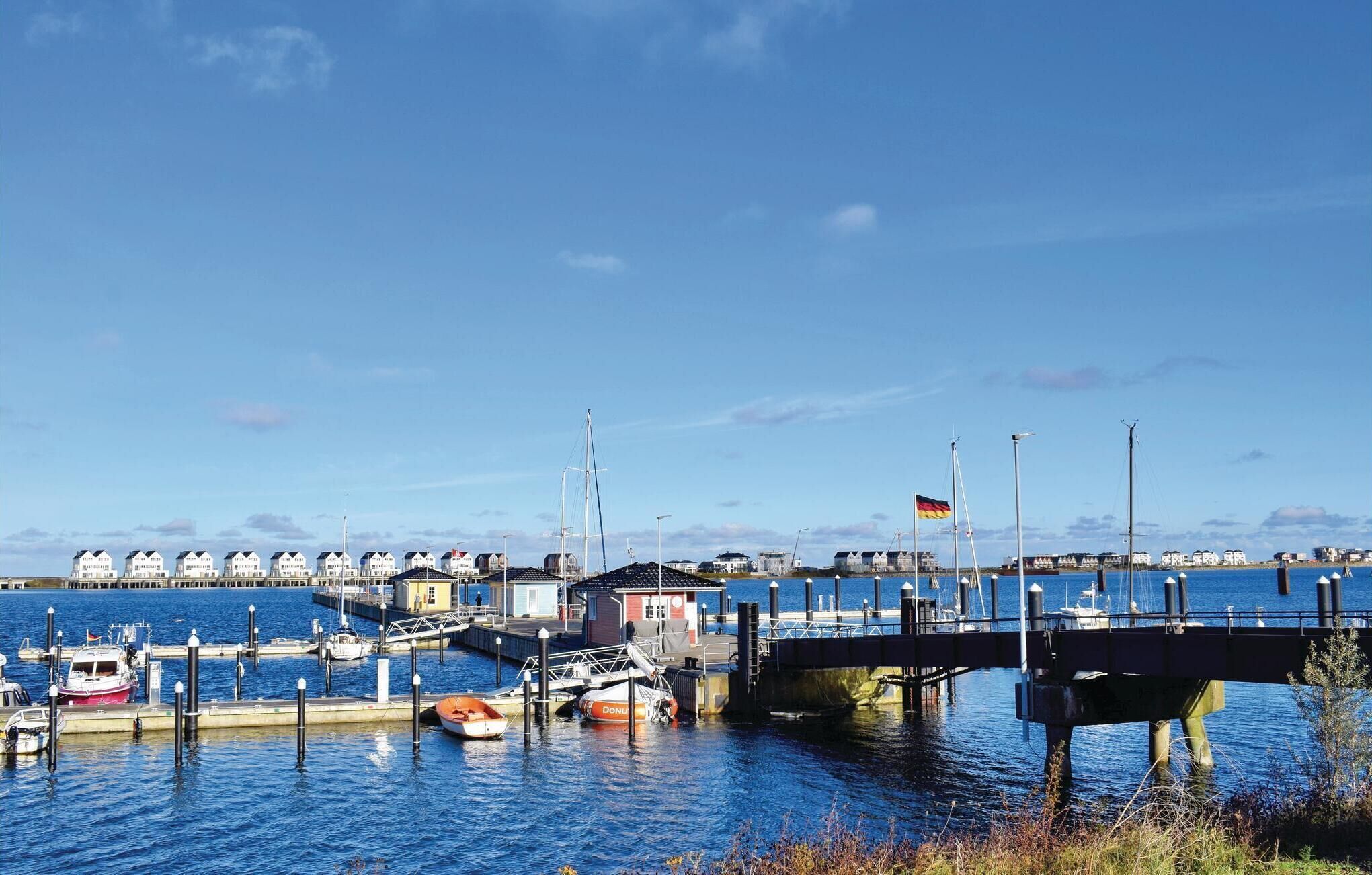 A marina with boats docked, a bridge, and buildings in the background.