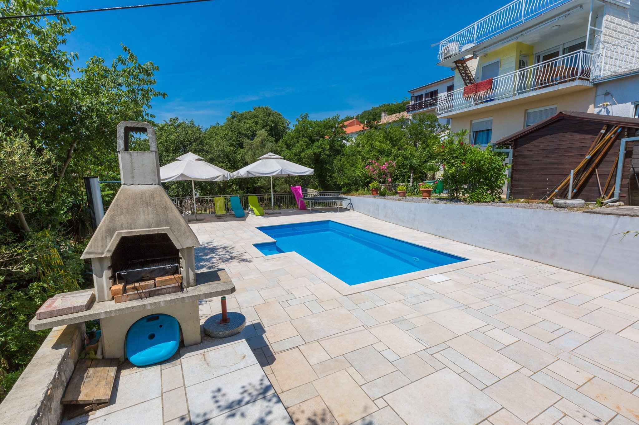 Ein Garten mit Schwimmbad, Grill und Sitzgelegenheit im Freien.