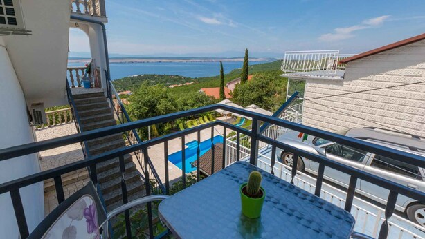 Varanda com vista para uma piscina e um corpo d'água.
