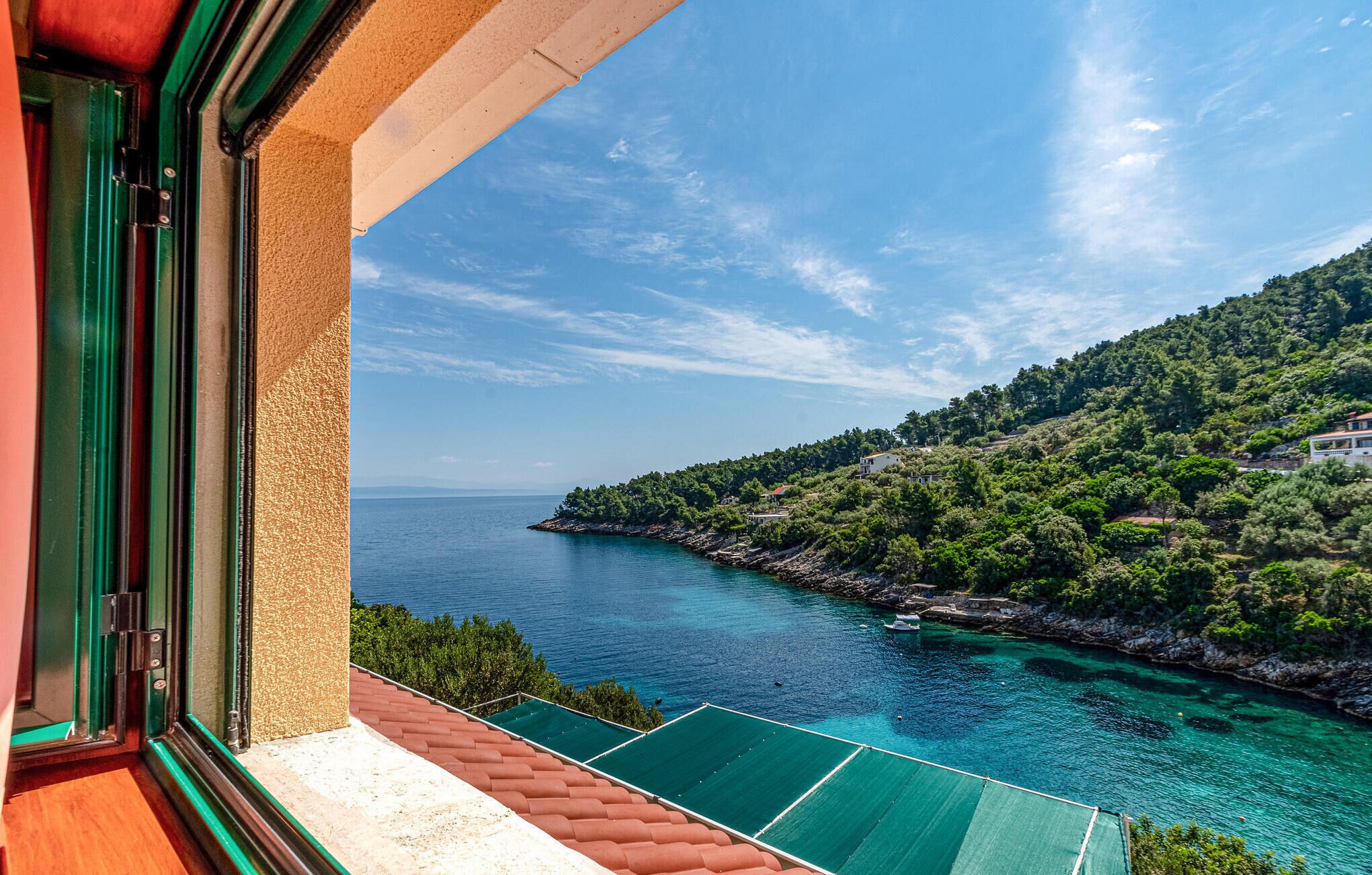 Ein Balkon mit Blick auf eine Küstenlandschaft, einschließlich eines Gewässers und einer bewachsenen Hügelkette.