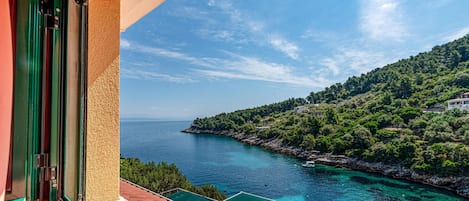 Ein Balkon mit Blick auf eine Küstenlandschaft, einschließlich eines Gewässers und einer bewachsenen Hügelkette.