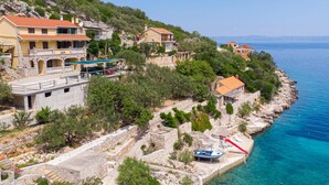 A coastal property with stone buildings, a boat dock, and a clear view of the sea.