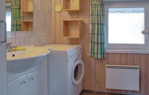 A compact bathroom with a washing machine, a sink, and a window with a view of the sea.