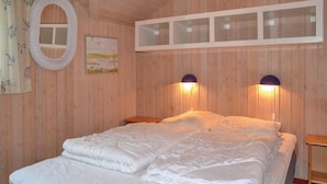 A wooden-paneled room with a bed, two wall-mounted lamps, a mirror, and a framed picture. - 3 bedroom cozy home in Oksbøl (Oksbøl)