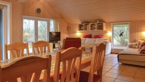 A cozy wooden cabin interior with a dining area, a TV, a sofa, and a bookshelf. - 3 bedroom cozy home in Oksbøl (Oksbøl)