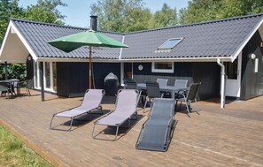 A covered outdoor area with a table and chairs, lounge chairs, and a green umbrella.
