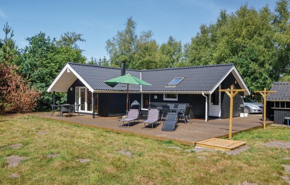 A modern house with a covered patio, outdoor seating, and a carport.