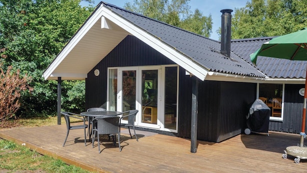 A modern house with a covered patio area, featuring a dining table and chairs, and a large window. - 3 bedroom cozy home in Oksbøl (Oksbøl)