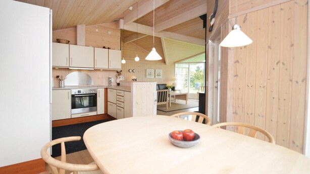 Una cocina moderna con armarios de madera, horno empotrado e iluminación colgante.