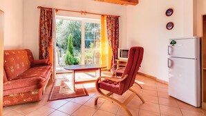 Un salon avec un canapé, un fauteuil rouge, une télévision et un réfrigérateur.