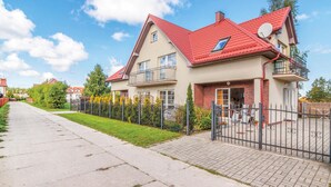 Une maison à deux étages avec un toit rouge, un balcon et une cour clôturée.