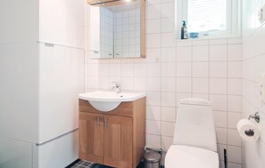 A bathroom with a white sink, wooden cabinet, and a toilet. - 4 bedroom stunning home in Slite (Slite)