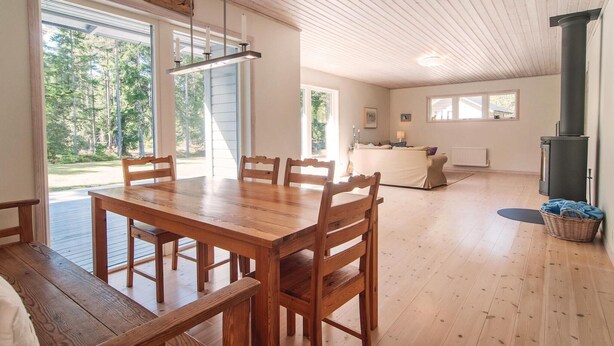 Un comedor espacioso con una mesa y sillas de madera, ventanas amplias que ofrecen vistas al exterior, y una sala de estar acogedora con chimenea.