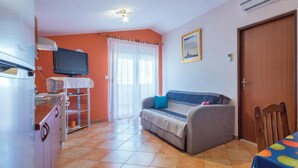 Un espacio habitable compacto con kitchenette, un sofá, una mesa de comedor y un televisor.