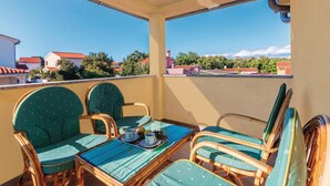 Un balcón con sillas de mimbre y una mesa, con vistas a una zona residencial con casas y árboles.