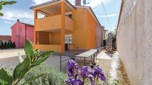 Un edificio de dos pisos con terraza abierta y una mesa de ping pong.