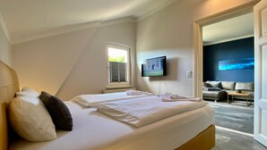 Een moderne hotelkamer met een groot bed, een aan de muur bevestigde televisie en uitzicht op het buitengebied.
