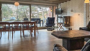 A spacious room with a large dining table and chairs, a fireplace, and a television mounted on the wall. - Awesome home in Rømø with kitchen (Rømø)