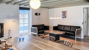 A dining area with a wooden table and chairs, a black leather couch, and a fireplace. - Awesome home in Rømø with kitchen (Rømø)
