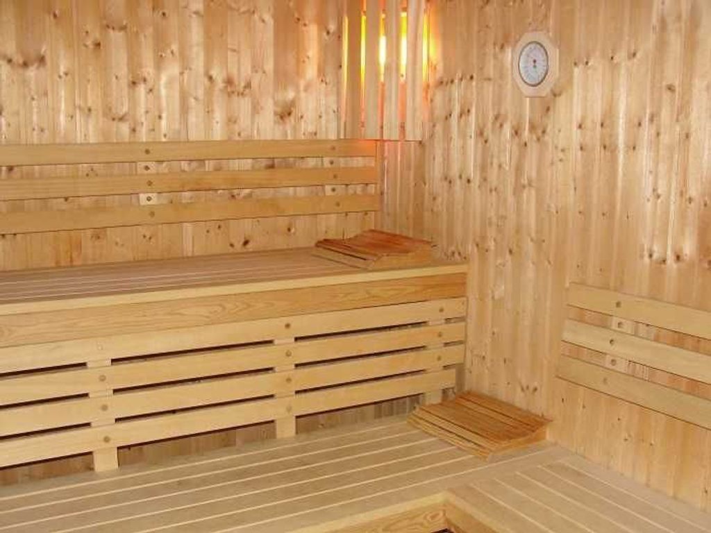 Un sauna en bois, doté de bancs et d’un panneau de commande.