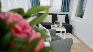 Ein modernes Wohnzimmer mit grauem Sofa, weißem Couchtisch und einer Zimmerpflanze.