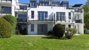 Ein mehrgeschossiges Wohnhaus mit Balkonen, einem gepflegten Rasen und blauem Himmel.