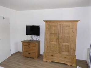 Ein Zimmer mit einem Holzkasten, einem Fernseher auf einem Schrank und einer Tür.