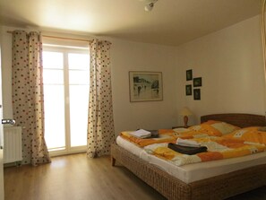 Une chambre à coucher avec un lit, une fenêtre avec des rideaux, un radiateur et un mur décoré de tableaux.