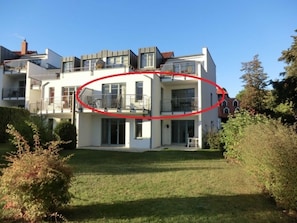 Ein modernes, zweistöckiges Haus mit Balkon, gepflegtem Rasen und blauem Himmel.