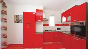A kitchen with red cabinets, a microwave, a stove, and a large oven. - 1 bedroom nice apartment in Makarska (Makarska)