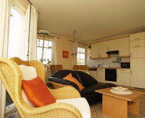 Un salon avec des meubles en osier et un coin repas avec une table.