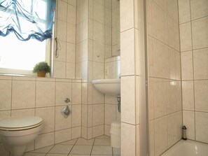 Un baño con inodoro, lavabo y zona de ducha.