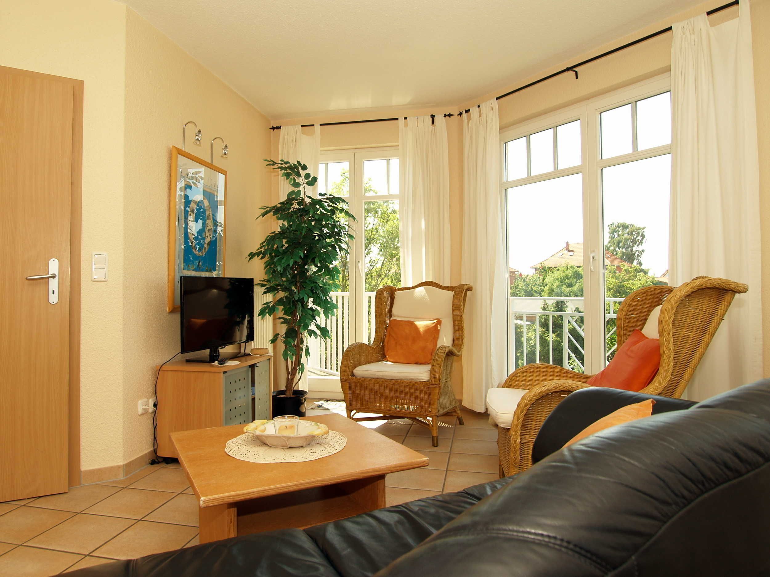 A living room with a television, a dining table with a bowl of fruit, a chair, and a sofa.