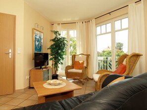 Una sala de estar con televisión, una mesa de comedor con un frutero, una silla y un sofá.