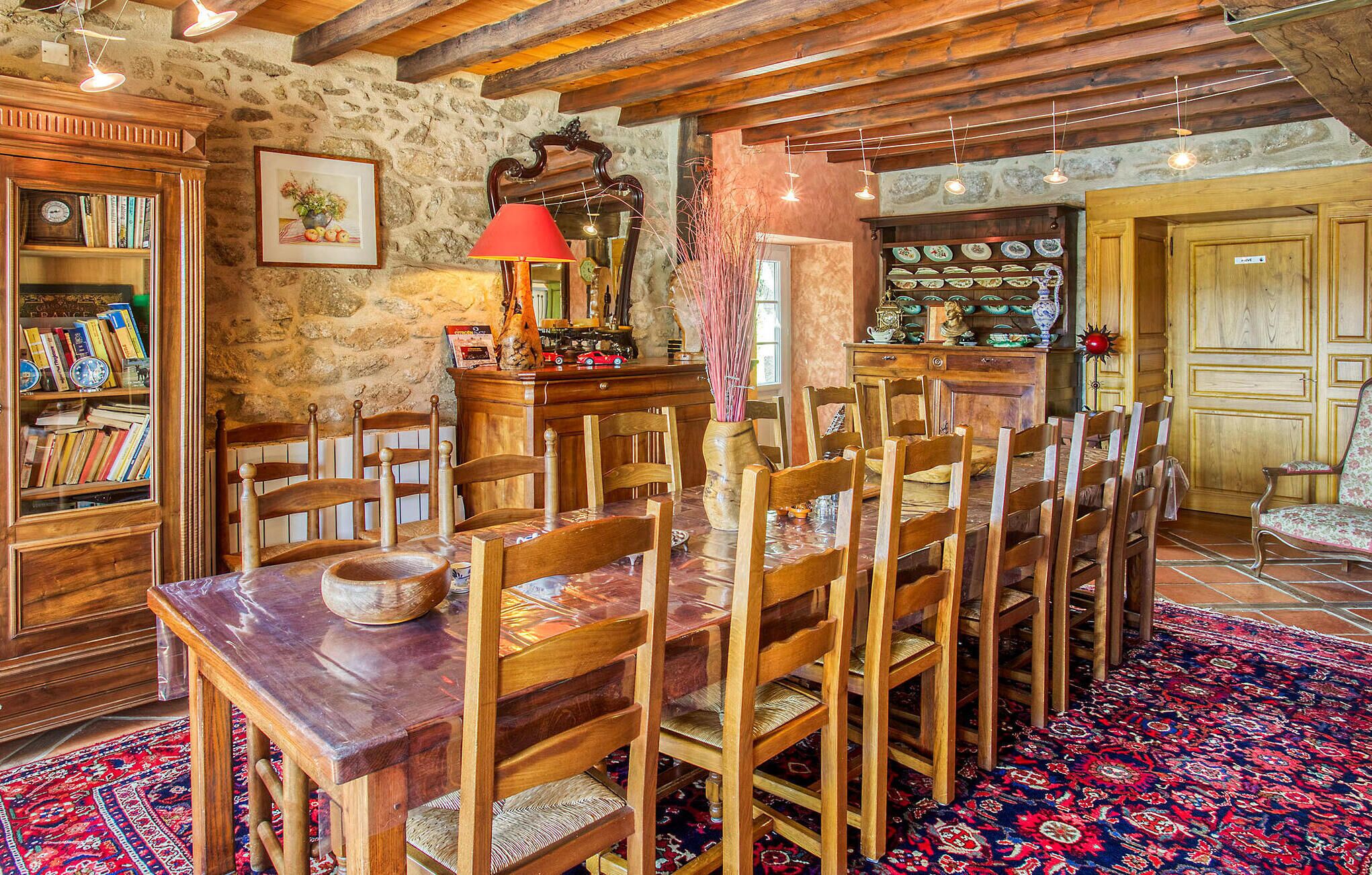 Un espace repas avec des chaises en bois et une table, entouré de murs en pierre et de poutres en bois.