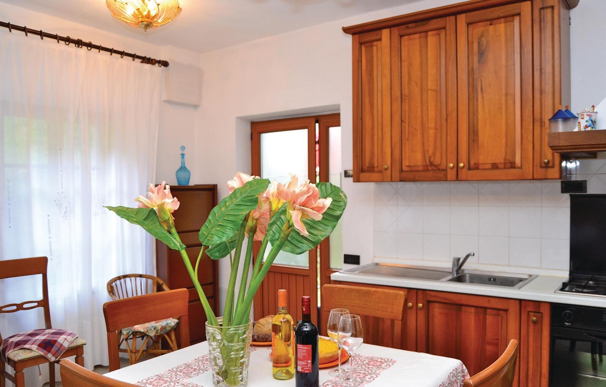 A kitchen with wooden cabinets, a dining table with chairs, and a vase with flowers.