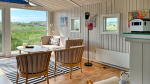 Ein gemütliches Zimmer mit Holzboden, einem runden Tisch und zwei Stühlen. Ein Fenster bietet Blick auf grüne Hügel.
