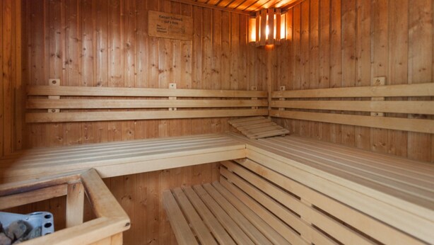 Sauna, jossa on puiset penkit ja seinällä kyltti.